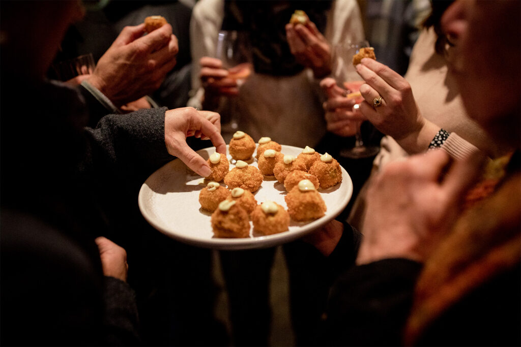 A group of people standing around a plate of delicious canapés at a Hamlet event.